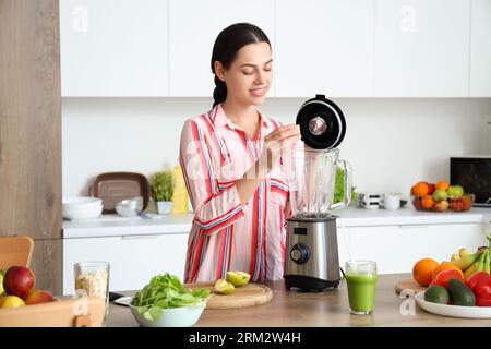 Young woman making smoothie with apple in blender at home Stock Photo