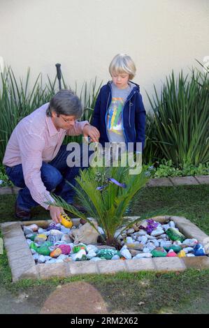 Bildnummer: 59910932  Datum: 27.06.2013  Copyright: imago/Xinhua (130627) -- JOHANNESBURG, June 27, 2013 (Xinhua) -- A father talks with his son beside colorful stones with best wishes for South Africa s anti-apartheid icon Nelson Mandela outside his residence in Johannesburg, South Africa, June 27, 2013. South African President Jacob Zuma has canceled his scheduled visit to Mozambique after visiting former president Nelson Mandela in hospital, the Presidency said Wednesday night. (Xinhua/Guo Xinghua) (jl) SOUTH AFRICA-JOHANNESBURG-MANDELA-ZUMA-TRIP-CANCEL PUBLICATIONxNOTxINxCHN Gesellschaft R Stock Photo