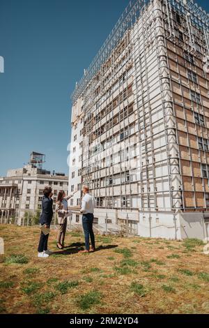 Giovane team di architetti che parla di progetti all'aperto Foto Stock