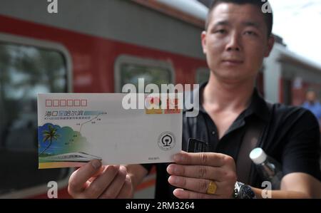 Bildnummer: 59930882 Datum: 02.07.2013 Copyright: imago/Xinhua (130702) -- HAIKOU, 2 luglio 2013 (Xinhua) -- Un passeggero mostra una busta ricordo per il primo treno diretto da Haikou a Harbin alla stazione ferroviaria di Haikou a Haikou, capitale della provincia di Hainan della Cina meridionale, 2 luglio 2013. Il treno K1122/3 dal sud della Cina di Haikou al nord-est della Cina di Heilongjiang ha lasciato Haikou martedì, un giorno dopo la data di partenza originale a causa della tempesta tropicale Rumbia. Il treno, che percorre 4.458 chilometri per 65 ore, ha collegato la capitale più meridionale della Cina, Haikou, della provincia di Hainan Foto Stock