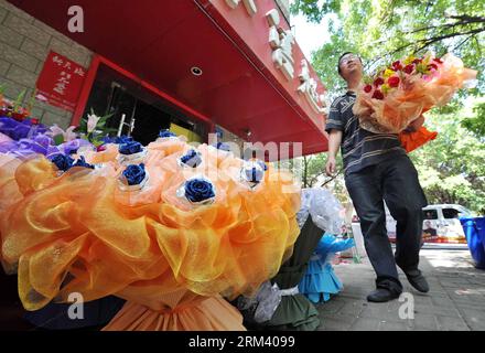 Bildnummer: 60348782  Datum: 12.08.2013  Copyright: imago/Xinhua (130812) -- YINCHUAN, Aug. 12, 2013 (Xinhua) -- A man holding flowers passes by a flower shop ahead of the Qixi Festival, or Chinese Valentine s Day, in Yinchuan, capital of northwest China s Ningxia Hui Autonomous Region, Aug. 12, 2013. The Qixi Festival, which falls on Aug. 13 this year, originates from a folk tale about a fairy named Zhinu who marries a mortal named Niulang. The marriage allegedly enraged the Goddess of Heaven, who created the Milky Way to separate them. Supposedly, the pair of lovers are reunited for a single Stock Photo