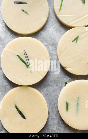Vista dall'alto dell'impasto crudo di biscotti al rosmarino, dell'impasto di biscotti al rosmarino che sta per essere cotto, processo di preparazione dei biscotti allo zucchero al rosmarino Foto Stock