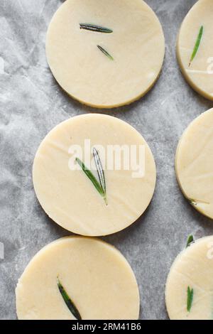 Vista dall'alto dell'impasto crudo di biscotti al rosmarino, dell'impasto di biscotti al rosmarino che sta per essere cotto, processo di preparazione dei biscotti allo zucchero al rosmarino Foto Stock