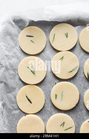 Vista dall'alto dell'impasto crudo di biscotti al rosmarino, dell'impasto di biscotti al rosmarino che sta per essere cotto, processo di preparazione dei biscotti allo zucchero al rosmarino Foto Stock