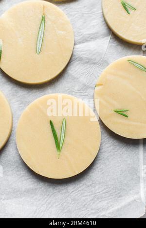 Vista dall'alto dell'impasto crudo di biscotti al rosmarino, dell'impasto di biscotti al rosmarino che sta per essere cotto, processo di preparazione dei biscotti allo zucchero al rosmarino Foto Stock