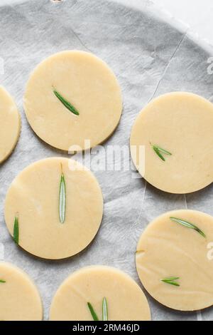 Vista dall'alto dell'impasto crudo di biscotti al rosmarino, dell'impasto di biscotti al rosmarino che sta per essere cotto, processo di preparazione dei biscotti allo zucchero al rosmarino Foto Stock