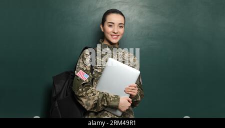 Educazione militare. Cadetto con zaino e laptop vicino alla lavagna verde Foto Stock