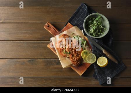 Gustosi schnitzels serviti con limone e microgreen su un tavolo di legno, piatti. Spazio per il testo Foto Stock