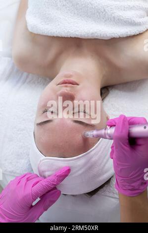 Top View cosmetologo che fa iniezione di mesoterapia con Dermapen sul viso di giovane donna per ringiovanimento nel centro termale. Paziente che riceve ago Foto Stock