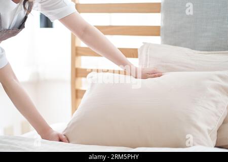 Donna asiatica che fa un letto in camera da letto Foto Stock