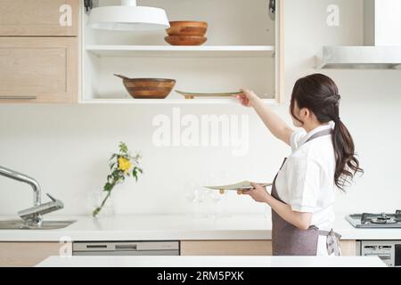 Donna asiatica che organizza la cucina Foto Stock