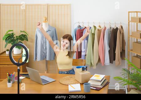 Concetto mercantile in linea, riuscito stilista delizioso con i vestiti effluenti in tensione di vendite. Foto Stock