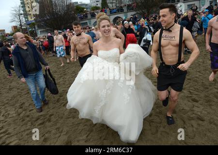 VANCOUVER, 1 gennaio 2014 - i novelli sposi Dana (C) e Fraser Hammoud-Goodwin (R) prendono parte alla 94a edizione annuale di Polar Bear Swim 2014 a Vancouver, Canada, 1 gennaio 2014. Il Vancouver Polar Bear Swim ha celebrato il suo 94° anniversario il giorno di Capodanno, quando centinaia di rivelatori in costumi a tema che spaziano dai supereroi alle renne e alle sirene si sono schiantate nel mare, divertendosi tra le onde gelide. (Xinhua/Sergei Bachlakov) CANADA-VANCOUVER-POLAR BEAR SWIM PUBLICATIONxNOTxINxCHN Vancouver 1 gennaio 2014 gli sposi novelli Dana C e Fraser Hammoud Goodwin r prendono parte alla 94a annuale Polar Bear Swim 2014i. Foto Stock