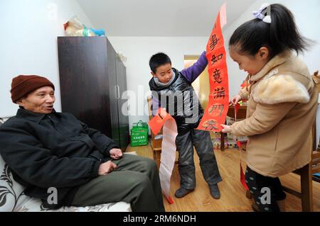 (140122) -- HANGZHOU, 22 gennaio 2014 (Xinhua) -- Cao Yichen (R), una bambina di 9 anni, e un giovane ragazzo inviano distici cinesi scritti da loro stessi a un vecchio Xu Hongda, come regali per salutare l'imminente Festival di Primavera, nella città di Hangzhou, capitale della provincia dello Zhejiang della Cina orientale, 22 gennaio 2014. I cinesi hanno la tradizione di fissare il couplet, che sono rotoli rossi con frasi rime, alle loro porte durante il Festival di Primavera, sperando che possa portare fortuna. Il Festival di primavera cade il 31 gennaio di quest'anno. (Xinhua/Ju Huanzong) (ry) CHINA-HANGZHOU-SPRING FESTIVAL-CUSTOM (CN) PUBLICATIONxNOTxINxCHN Foto Stock