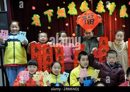 (140122) -- HANGZHOU, 22 gennaio 2014 (Xinhua) -- i bambini mostrano i loro distici cinesi e le opere di taglio della carta del carattere cinese fu (felicità), che saranno inviati agli anziani come regali per salutare il prossimo Festival di Primavera, nella città di Hangzhou, capitale della provincia dello Zhejiang della Cina orientale, 22 gennaio 2014. I cinesi hanno la tradizione di fissare il couplet, che sono rotoli rossi con frasi rime, alle loro porte durante il Festival di Primavera, sperando che possa portare fortuna. Il Festival di primavera cade il 31 gennaio di quest'anno. (Xinhua/Ju Huanzong) (ry) CHINA-HANGZHOU-SPRING FESTIVAL-CUSTOM (CN) PUBLICATIONx Foto Stock