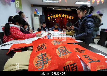 (140122) -- HANGZHOU, 22 gennaio 2014 (Xinhua) -- Pan Xiaoyan (1st R), una bambina di 8 anni, e altri bambini scrivono distici cinesi per salutare il prossimo Festival di Primavera, nella città di Hangzhou, capitale della provincia dello Zhejiang della Cina orientale, 22 gennaio 2014. I cinesi hanno la tradizione di fissare il couplet, che sono rotoli rossi con frasi rime, alle loro porte durante il Festival di Primavera, sperando che possa portare fortuna. Il Festival di primavera cade il 31 gennaio di quest'anno. (Xinhua/Ju Huanzong) (ry) CHINA-HANGZHOU-SPRING FESTIVAL-CUSTOM (CN) PUBLICATIONxNOTxINxCHN Hangzhou 22 gennaio 2014 XINHUA Pan Xiaoyan 1st Foto Stock