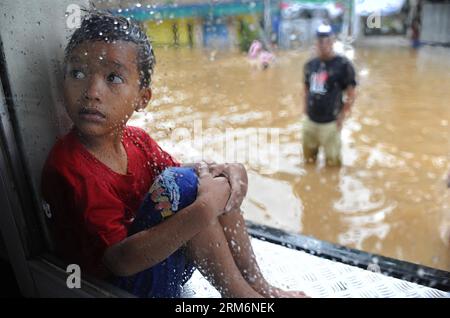 (140122) -- JAKART, 22 gennaio 2014 (Xinhua) -- Un ragazzo siede in una fermata dell'autobus allagata a Giacarta, Indonesia, 22 gennaio 2014. Nella capitale indonesiana di Giacarta, alcuni sfollati hanno iniziato a tornare a casa per pulire le loro case mentre l'alluvione si allontana, ma sono ancora riluttanti a tornare di notte, secondo i funzionari. (Xinhua/Zulkarnain) (zjl) INDONESIA-JAKARTA-FLOOD PUBLICATIONxNOTxINxCHN 22 gennaio 2014 XINHUA a Boy siede in una fermata dell'autobus allagata a Giacarta Indonesia 22 gennaio 2014 nella capitale indonesiana di Giacarta alcune delle celebrità sfollate hanno iniziato a restituire le case a Clean Foto Stock