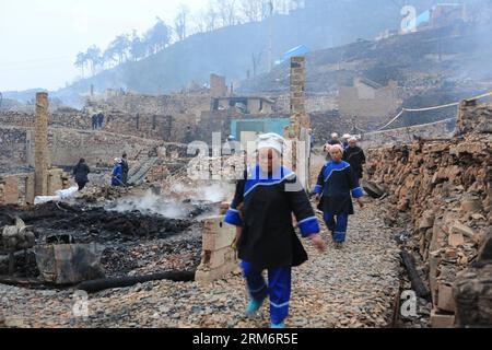 (140126) -- ZHENYUAN, 26 gennaio 2014 (Xinhua) -- le persone passano davanti alle rovine di case bruciate nel villaggio di Baojing Dong della contea di Zhenyuan, provincia di Guizhou nella Cina sud-occidentale, 26 gennaio 2014. Un incendio scoppiò alle 23:30 di sabato nel villaggio e distrusse più di 100 case. Il villaggio di Baojing Dong, costruito 300 anni fa, è il più grande villaggio di Dong a Qiandongnan Miao e nella prefettura autonoma di Dong a Guizhou. Era uno degli insediamenti più ben conservati della Cina, noto per le sue antiche abitazioni in stile Dong. Ospita 470 famiglie e quasi 2.000 abitanti. Nessuna vittima è stata segnalata a. Foto Stock