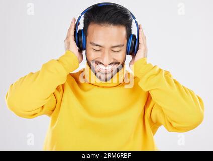 Uomo, cuffie e ascolto con sorriso, studio e ascolto con abbonamento streaming su sfondo bianco. Giovane messicano, studente o moda Foto Stock