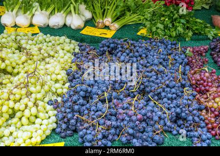 Uva rossa e bianca con alcune verdure in vendita al mercato Foto Stock