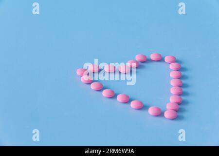 Cuore fatto di medicinali rosa su sfondo blu. Il concetto di uno stile di vita sano e una visita medica tempestiva. Foto Stock