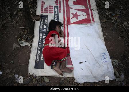 Una ragazza del gruppo etnico Ngabe Bugle dorme in un campo vicino alla riva del fiume Tabasara nella regione indigena Ngabe Bugle, 450 km a ovest di Panama City, capitale di Panama, il 24 febbraio 2014. La regione indigena di Ngabe Bugle si trova nella regione occidentale di Panama e copre un'area di 6.968 km quadrati, con il 91% della sua popolazione che vive in estrema povertà. I leader indigeni della regione di Ngabe Bugle hanno dichiarato un allarme nazionale , a causa dell' avviso di sfratto emesso da una società che sta sviluppando il progetto idroelettrico Barro Blanco . Il progetto utilizzerà l'acqua del fiume Tabasara Foto Stock