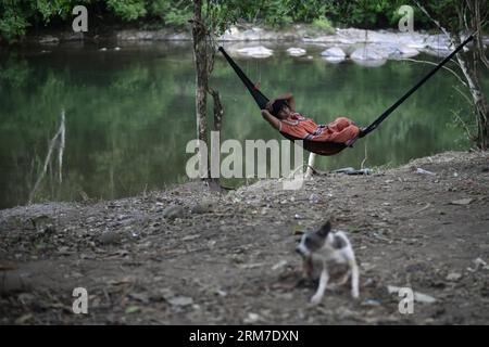 Una donna del gruppo etnico Ngabe Bugle riposa in un campo vicino alla riva del fiume Tabasara nella regione indigena Ngabe Bugle, 450 km a ovest di Panama, capitale di Panama, il 24 febbraio 2014. La regione indigena di Ngabe Bugle si trova nella regione occidentale di Panama e copre un'area di 6.968 km quadrati, con il 91% della sua popolazione che vive in estrema povertà. I leader indigeni della regione di Ngabe Bugle hanno dichiarato un allarme nazionale , a causa dell' avviso di sfratto emesso da una società che sta sviluppando il progetto idroelettrico Barro Blanco . Il progetto utilizzerà l'acqua del fiume Tabasara Foto Stock