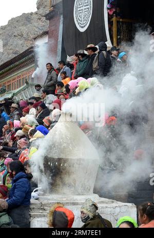 (140228) -- LHASA, 28 febbraio 2014 (Xinhua) -- i buddisti tibetani guardano un rituale di danza Cham tenuto per celebrare l'imminente Losar al monastero di Tsurphu nella contea di Doilungdeqen di Lhasa, capitale della regione autonoma del Tibet della Cina sud-occidentale, 28 febbraio 2014. La danza Cham è un rituale eseguito dai monaci buddisti tibetani per esorcizzare gli spiriti maligni. I ballerini indossano maschere di vari animali e figure mitiche mentre si esibiscono con l'accompagnamento della musica religiosa. Al monastero di Tsurphu, una base principale della scuola Kagyu nel buddismo tibetano, la danza Cham viene solitamente eseguita due giorni prima della L Foto Stock