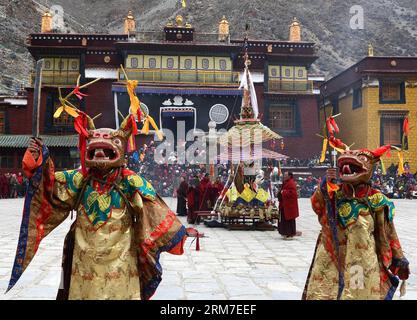 (140228) -- LHASA, 28 febbraio 2014 (Xinhua) -- i monaci buddisti tibetani mascherati si esibiscono durante un rituale di danza Cham tenuto per celebrare l'imminente Losar presso il monastero di Tsurphu nella contea di Lhasa, capitale della regione autonoma Tibet del sud-ovest della Cina, 28 febbraio 2014. La danza Cham è un rituale eseguito dai monaci buddisti tibetani per esorcizzare gli spiriti maligni. I ballerini indossano maschere di vari animali e figure mitiche mentre si esibiscono con l'accompagnamento della musica religiosa. Al monastero di Tsurphu, una base principale della scuola Kagyu nel buddismo tibetano, la danza Cham viene solitamente eseguita TW Foto Stock