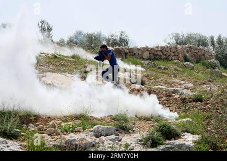 (140319) -- HEBRON, 19 marzo 2014 (Xinhua) -- il manifestante palestinese corre per coprire il gas sparato dai soldati israeliani durante gli scontri dopo che l'adolescente palestinese Yussef Shawamreh è stato ucciso, vicino al recinto di sicurezza nella città di Hebron in Cisgiordania il 19 marzo 2014. Shawamreh, sedicenne, è stato colpito vicino al villaggio palestinese di al-Ramadin, a sud di Hebron, quando lui e tre dei suoi amici stavano tentando di attraversare la recinzione di separazione tra Israele e i territori palestinesi. (Xinhua/Mamoun Wazwaz) MIDEAST-HEBRON-CLASHES PUBLICATIONxNOTxINxCHN Hebron 19 marzo 2014 XINHUA fuga PALESTINESE Foto Stock