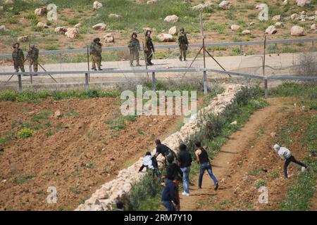 (140319) -- HEBRON, 19 marzo 2014 (Xinhua) -- i manifestanti palestinesi lanciano pietre contro i soldati israeliani durante gli scontri dopo che l'adolescente palestinese Yussef Shawamreh è stato ucciso, vicino al recinto di sicurezza nella città di Hebron in Cisgiordania il 19 marzo 2014. Shawamreh, sedicenne, è stato colpito vicino al villaggio palestinese di al-Ramadin, a sud di Hebron, quando lui e tre dei suoi amici stavano tentando di attraversare la recinzione di separazione tra Israele e i territori palestinesi. (Xinhua/Mamoun Wazwaz) MIDEAST-HEBRON-CLASHES PUBLICATIONxNOTxINxCHN Hebron 19 marzo 2014 XINHUA PALESTINESE scaglia pietre CONTRO Israele Foto Stock