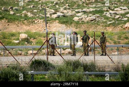 (140319) -- HEBRON, 19 marzo 2014 (Xinhua) -- soldati israeliani sparano ai manifestanti palestinesi durante gli scontri dopo che l'adolescente palestinese Yussef Shawamreh è stato ucciso, vicino al recinto di sicurezza nella città di Hebron in Cisgiordania il 19 marzo 2014. Shawamreh, sedicenne, è stato colpito vicino al villaggio palestinese di al-Ramadin, a sud di Hebron, quando lui e tre dei suoi amici stavano tentando di attraversare la recinzione di separazione tra Israele e i territori palestinesi. (Xinhua/Mamoun Wazwaz) MIDEAST-HEBRON-CLASHES PUBLICATIONxNOTxINxCHN Hebron 19 marzo 2014 soldati israeliani XINHUA sparano a favore dei PALESTINESI Foto Stock