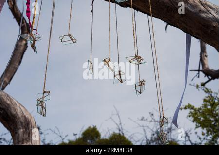 Gruppo simbolico di pezzi di vetro sulle corde con il cielo e il vecchio albero come sfondo. Astratto, tema decorativo Foto Stock