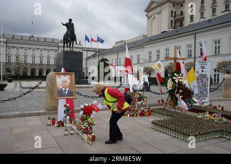 (140410) -- VARSAVIA, 10 aprile 2014 (Xinhua) -- Una donna piange per le vittime dell'incidente aereo davanti all'ufficio presidenziale di Varsavia, in Polonia, 10 aprile 2014. La Polonia ha assistito al quarto anniversario del disastro aereo del 2010 a Smolensk, in Russia, che ha ucciso l'ex presidente polacco Lech Kaczynski, sua moglie e numerosi VIP. Il 10 aprile 2010, un aereo del governo polacco Tupolev-154M che trasportava l'allora presidente Lech Kaczynski, sua moglie e una grande delegazione di VIP si schiantò vicino a un aeroporto militare a Smolensk, uccidendo tutti a bordo. (Xinhua/Gao fan) (dzl) POLONIA-VARSAVIA-ANNIVERSARIO-PRESIDENTE PL Foto Stock