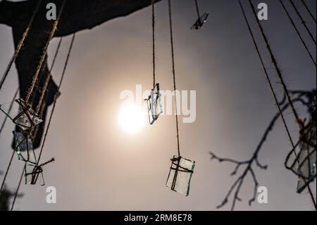 Gruppo di pezzi di vetro sulle corde davanti al sole con la luce che li attraversa. Astratto, tema decorativo Foto Stock