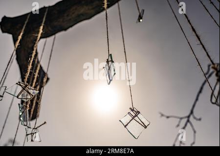 Gruppo di pezzi di vetro sulle corde del tronco davanti al sole con la luce che li attraversa. Astratto, arredamento, tema di sfondo Foto Stock