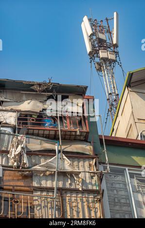 Un albero di trasmissione del telefono cellulare 5G fissato al tetto delle case delapidate nel centro di Hanoi, in Vietnam. Foto Stock