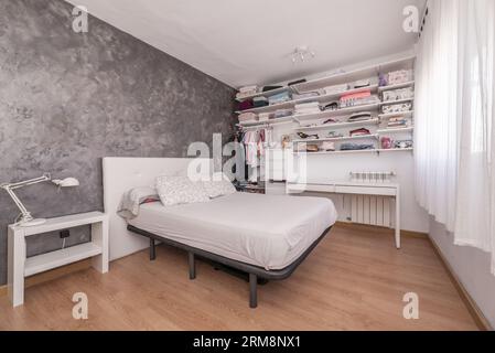 Letto confortevole e armadio in stile minimalista situato vicino alla  finestra con tende nella camera da letto moderna Foto stock - Alamy