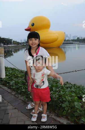 (140427) -- HO CHI MINH CITY, aprile 27 (Xinhua) -- i bambini posano per delle foto con l'anatra gigante di gomma nella zona residenziale di Phu My Hung a ho chi Minh City, Vietnam, 26 aprile 2014. Un'anatra di gomma alta 18 metri, che ha affascinato persone in tutto il mondo, sarà esposta presso il lago Crescent nella zona residenziale di Phu My Hung della città di HCM da aprile 27 a maggio 31, secondo quanto riportato dai media locali sabato. Disegnata dall'artista olandese Florentijn Hofman, l'anatra di gomma ha iniziato un tour intitolato "Spanding Joys Around the World" nel 2007. HCM City sarà la sedicesima sede in cui verrà esposta. (Xinhua/Tao Ju Foto Stock