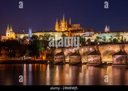 Vista notturna del Ponte Carlo attraverso il fiume Moldava a Praga con la Cattedrale di San La chiesa di Nicola a sinistra, il castello di Praga e la chiesa di San Cattedrale di Vito Foto Stock