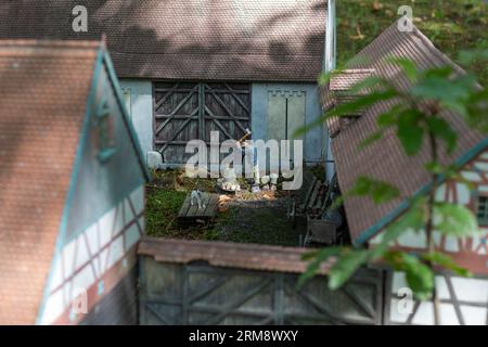 Il sole splende sul diorama in miniatura al Park Boheminium di Mariánské Lázně, Repubblica Ceca, raffigurante una fattoria storica con un contadino che taglia il legno Foto Stock