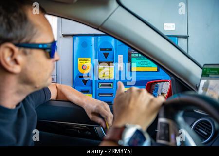 Alto Adige, Italia - 3 agosto 2023: Uomo in auto che paga con carta di credito presso un casello italiano per l'utilizzo dell'autostrada o delle autostrade Foto Stock