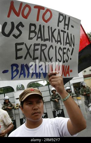 (140505) -- QUEZON CITY, 5 maggio 2014 (Xinhua) -- un attivista tiene un cartello davanti ai soldati filippini durante una manifestazione di protesta contro l'Enhanced Defense Cooperation Agreement (EDCA) fuori dalle porte del quartier generale delle forze Armate delle Filippine (AFP) a Camp Aguinaldo a Quezon City, Filippine, 5 maggio 2014. Gli attivisti condannano l'EDCA, in cui gli Stati Uniti avranno una maggiore presenza a rotazione nelle Filippine e avranno un maggiore accesso ai porti, agli aeroporti e alle basi militari del paese. I manifestanti stanno protestando anche contro il Balikatan 2014, wh Foto Stock