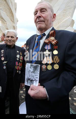 (140508) -- NETANYA (ISRAELE), 8 maggio 2014 (Xinhua) -- Un veterano della seconda guerra mondiale (R) ha una foto di se stesso come soldato accanto a un monumento che commemora la vittoria dell'Armata Rossa sovietica nella seconda guerra mondiale, durante una cerimonia che segna la vittoria alleata sulla Germania nazista a Yad LeBanim a Netanya, Israele, l'8 maggio 2014, un giorno prima del giorno della Vittoria. (Xinhua/JINI/Nimrod Gilgman) ISRAEL-NETANYA-VICTORY-COMMEMORATION PUBLICATIONxNOTxINxCHN Netanya Israel 8 maggio 2014 XINHUA A a World Was II Veteran r tiene una foto di se stesso come soldato accanto a un monumento che commemora Ting la Vittoria dei Sovi Foto Stock