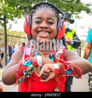 Londra, Regno Unito, 27 agosto 2023. Aliah, una giovane partecipante del gruppo con sua madre, si diverte a ballare alla parata. Gruppo mas Caribbean Sessions e giovani ballerini. Il carnevale di Notting Hill inizia con il carnevale dei bambini e con un percorso per famiglie. Si prevede che fino a due milioni di persone celebrino il carnevale di questo fine settimana festivo partecipando o guardando lungo il percorso del carnevale, presso impianti sonori, bancarelle e locali. Polveri e pitture colorate, in riconoscimento della tradizione caraibica e inizio delle festività del Carnevale di Notting Hill. Foto Stock