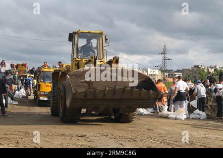 Un carrello elevatore passa mentre le persone costruiscono terrapieni riempiendo i sacchi di sabbia e costruendoli in un muro per proteggerli dalle inondazioni a Umka di Belgrado, Serbia, il 17 maggio 2014. In una breve pausa di piogge, la Serbia si impegnò al massimo delle capacità per assicurare argini sul fiume Sava e salvare le persone nella città di Obrenovac, devastata dalle inondazioni. (Xinhua/Wang Hui) SERBIA-BELGRADO-INONDAZIONI-TERRAPIENI PUBLICATIONxNOTxINxCHN un carrello elevatore fa strada mentre le celebrità COSTRUISCONO terrapieni riempiendo sacchi di sabbia e costruendoli in un muro per proteggere contro l'inondazione a Belgrado in Serbia IL 17 maggio 2014 in breve pausa dalla Rai Foto Stock