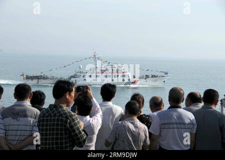 (140520) -- A BORDO DI WUZHISHAN, 20 maggio 2014 (Xinhua) -- cittadini cinesi a bordo della nave passeggeri Wuzhishan osservano una nave di pattuglia marina cinese, mentre la nave Wuzhishan si dirige verso Haikou, capitale della provincia di Hainan della Cina meridionale, il 20 maggio 2014. Il primo gruppo di lavoratori cinesi colpiti dalla violenza in Vietnam è arrivato al porto di Haikou martedì mattina. Il governo cinese ha inviato quattro navi domenica per evacuare i lavoratori cinesi colpiti dalla sommossa in Vietnam, dove la violenta violenza contro le aziende straniere dal 13 maggio ha causato la morte di due cittadini cinesi e più di 100 feriti.(Xi Foto Stock