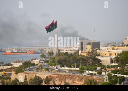 (140520) -- TRIPOLI, 20 maggio 2014 (Xinhua) -- il fumo sorge da un edificio durante un attacco a Tripoli, Libia, 19 maggio 2014. Lunedì, l'oratore del parlamento libico ha ordinato a una milizia filo-governativa di salvaguardare la capitale, appena un giorno dopo che il complesso del parlamento è stato attaccato da un gruppo militante fedele a un generale rinnegato. Il paese nordafricano ha assistito a una drastica escalation di violenza ed è diventato una base importante per i gruppi militanti canaglia dalla caduta dell'ex presidente Muammar Gheddafi nel 2011. (Xinhua/Zhang Yuan) LIBIA-TRIPOLI-MILIZIA PUBLICATIONxNOTxINxCHN Tripoli 20 maggio 2 Foto Stock