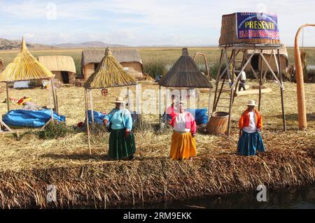 (140520) -- PUNO, 20 maggio 2014 (Xinhua) -- la gente si trova sull'isola galleggiante di Los Uros sul lago Titicaca, nella regione di Puno, Perù, 13 maggio 2014. Il lago Titicaca e le sue isole galleggianti nella regione di Puno del Perù hanno non solo attrazioni naturali, ma anche una cultura unica grazie alla popolazione quechua di Juliaca che vive lì. Il lago Titicaca si trova nell'altopiano di Collao, con le isole di Luna, Taquile, Amantani, Uros e Suriqui. (Xinhua/Luis Camacho)(zhf) PERU-PUNO-TITICACA LAKE-FLOATING ISLAND PUBLICATIONxNOTxINxCHN Puno 20 maggio 2014 le celebrità di XINHUA si trovano A Los Uros Floating Iceland AT Foto Stock