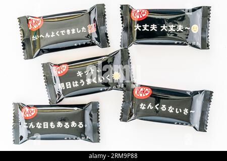 Diversi Kit Kat da mini bar giapponesi avvolti in nero in una piccola pila su uno sfondo bianco semplice. Foto Stock